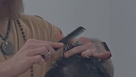 Derek combing and cutting a client's hair, close detail